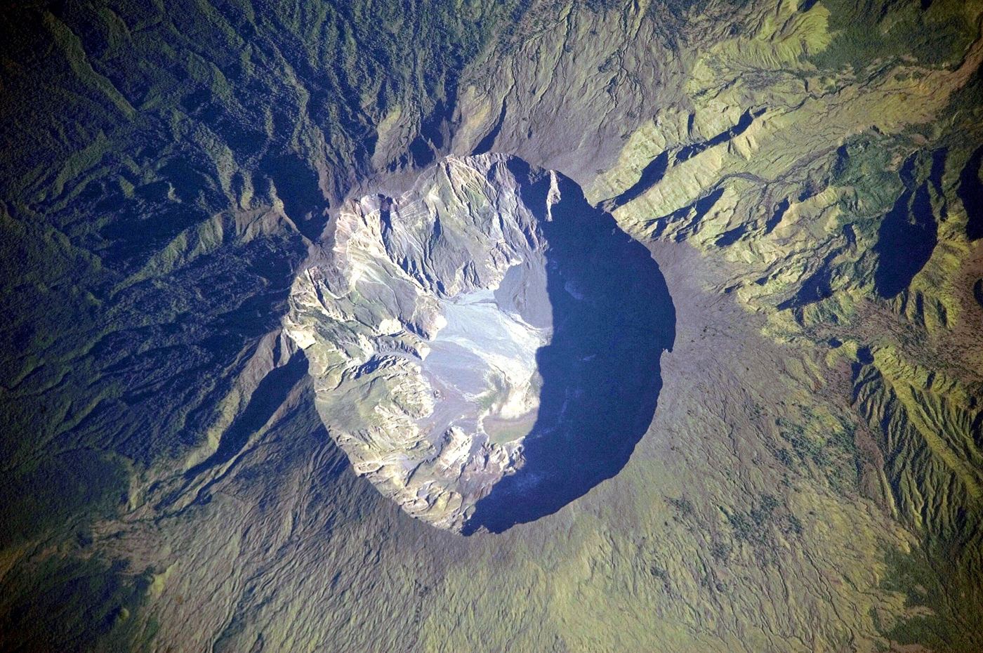 volcanic ash cloud rising above an island